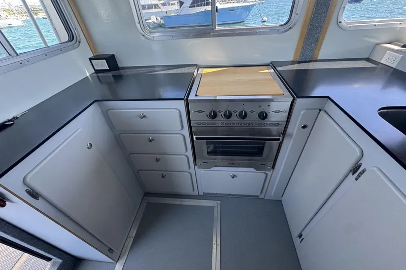 Slide: The Image of 2015 Armstrong Marine Power Cat kitchen with stove, cabinets, and ocean view. - 9