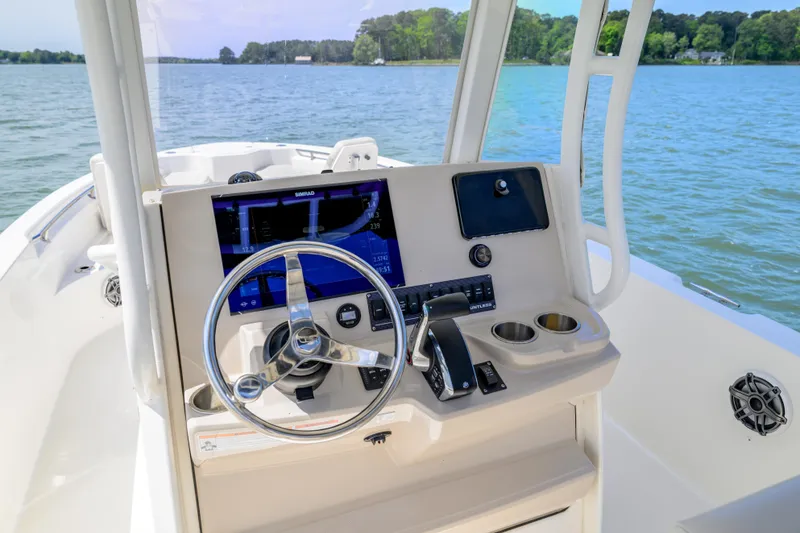 Slide: The Image of 2023 Boston Whaler 280 Dauntless helm with steering wheel and navigation display on a lake. - 15