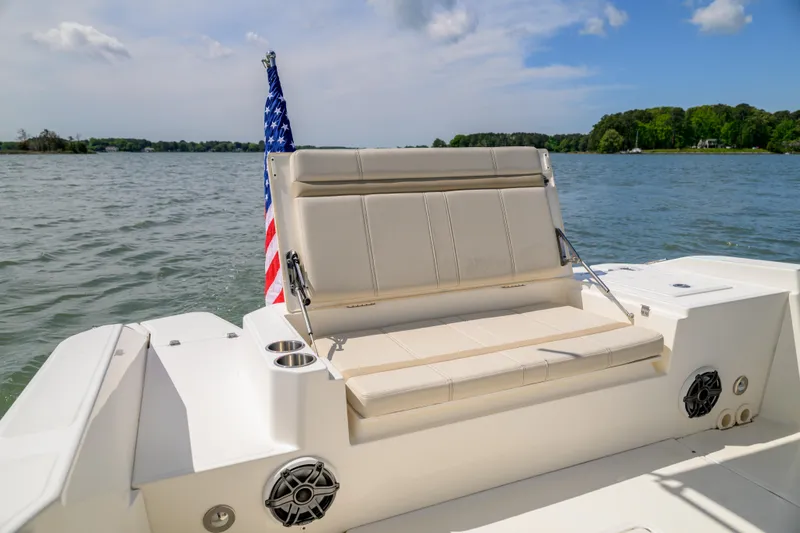 Slide: The Image of 2023 Boston Whaler 280 Dauntless boat with seating and American flag on a serene lake. - 17