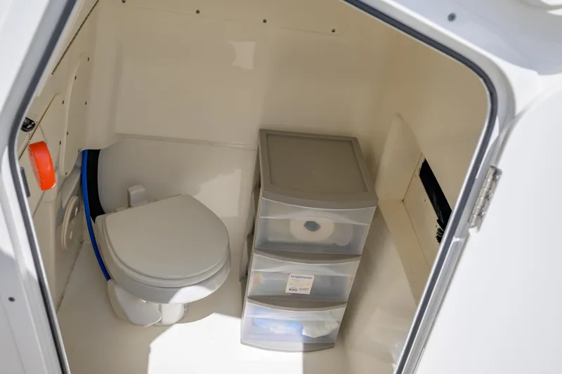 Slide: The Image of Interior of 2023 Boston Whaler 280 Dauntless boat, featuring a compact marine toilet. - 19