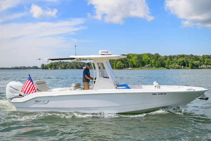 Slide: The Image of 2023 Boston Whaler 280 Dauntless boat cruising on a scenic lake with an American flag. - 2