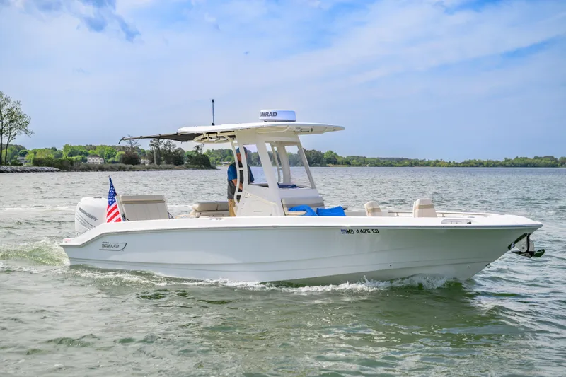 Slide: The Image of 2023 Boston Whaler 280 Dauntless cruising on a scenic lake under a clear blue sky. - 3