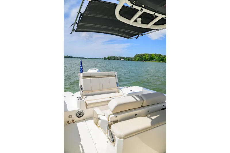 Slide: The Image of 2023 Boston Whaler 280 Dauntless boat interior with seating, canopy, and scenic lake view. - 9