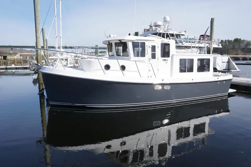 The Image of 2004 American Tug 34 docked in a marina, reflecting on calm water. - 0