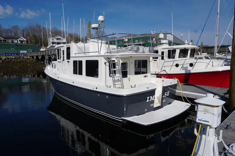 Slide: The Image of 2004 American Tug 34 docked at a marina, reflecting on calm water. - 1