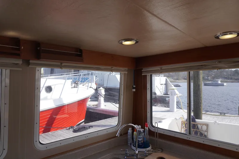 Slide: The Image of Interior view from a 2004 American Tug 34, showcasing marina and boats through windows. - 12