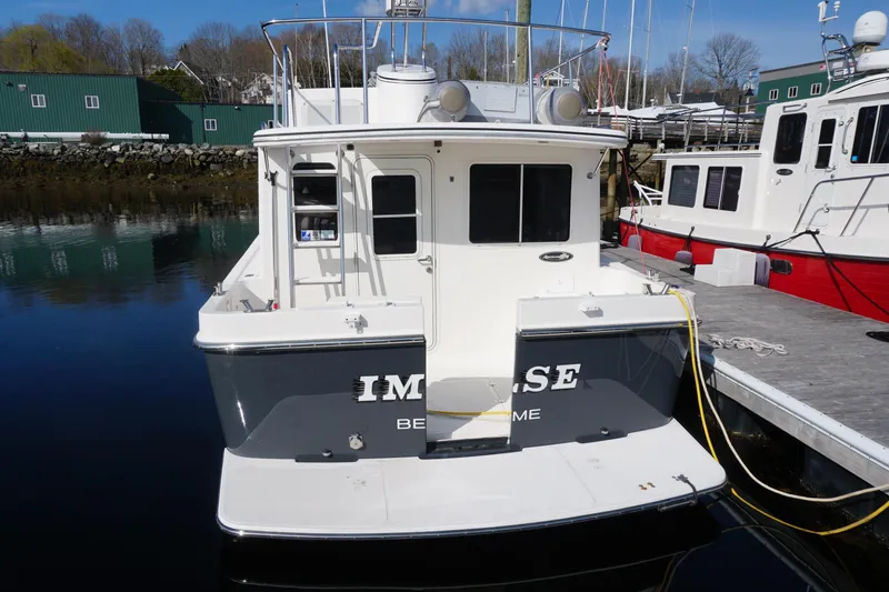 Slide: The Image of 2004 American Tug 34 docked at marina, rear view with calm water reflection. - 2