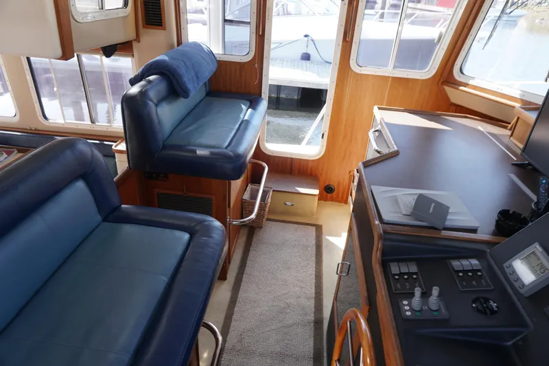 Slide: The Image of Interior of a 2004 American Tug 34, featuring blue seating and a navigation station. - 20