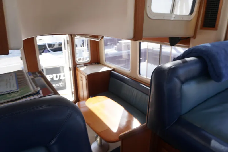 Slide: The Image of Interior of 2004 American Tug 34 with blue seating and wooden table. - 22