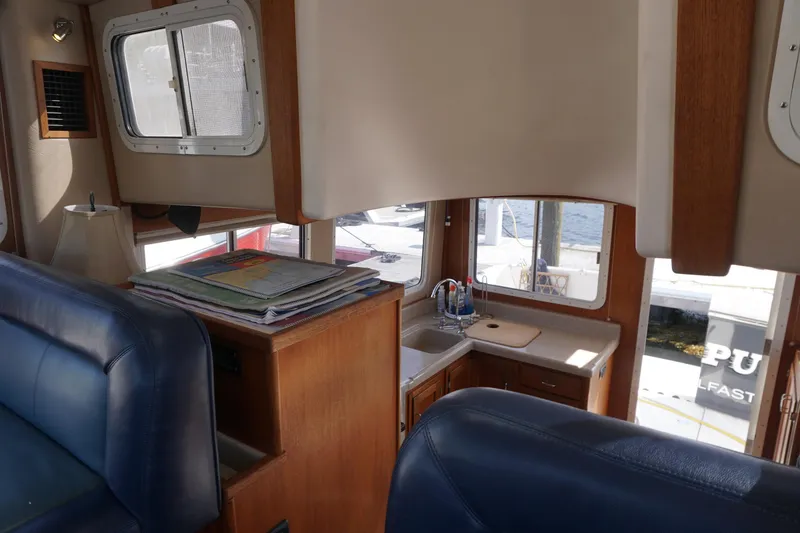 Slide: The Image of Interior of 2004 American Tug 34, featuring a compact kitchen and seating area. - 23