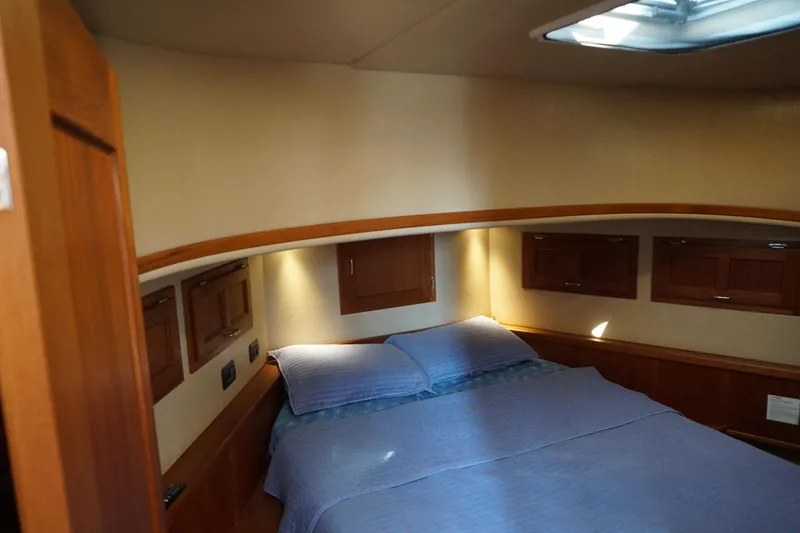 Slide: The Image of Cozy cabin interior of 2004 American Tug 34 with wood accents and comfortable bedding. - 27