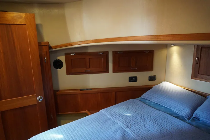 Slide: The Image of Cozy cabin interior of 2004 American Tug 34 with wooden accents and blue bedding. - 30