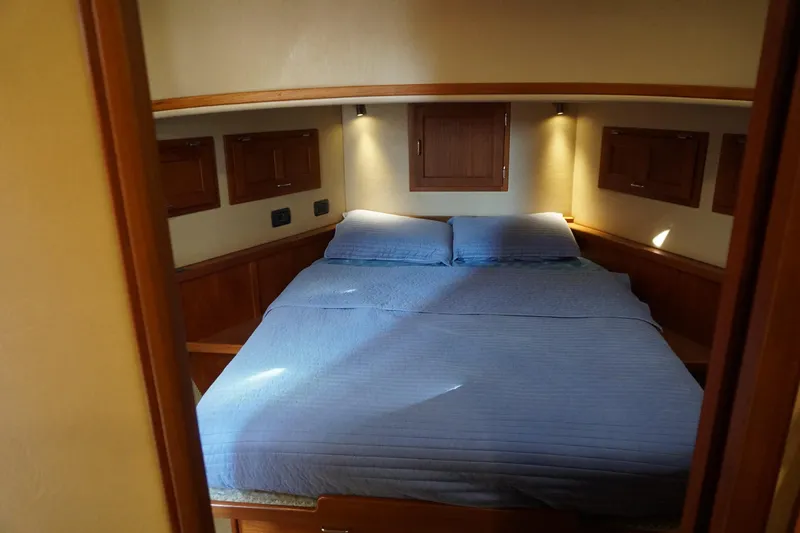 Slide: The Image of Cozy cabin interior of 2004 American Tug 34 with blue bedding and wooden accents. - 36