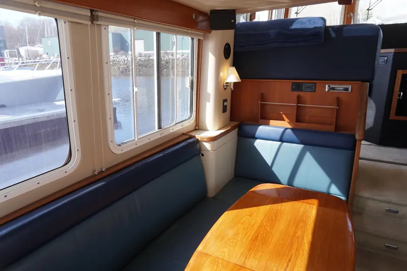 Slide: The Image of Interior of 2004 American Tug 34, featuring cozy seating and large windows with waterfront view. - 4