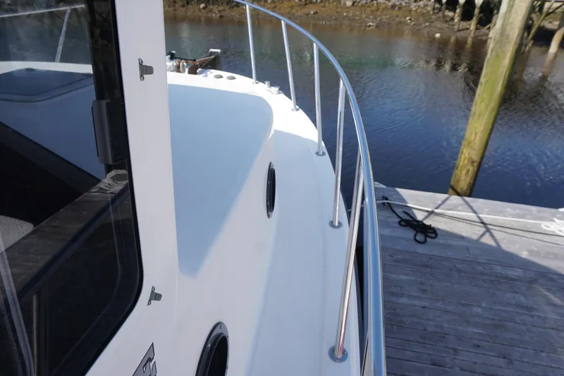 Slide: The Image of 2004 American Tug 34 boat docked, showcasing sleek deck and railing design. - 41