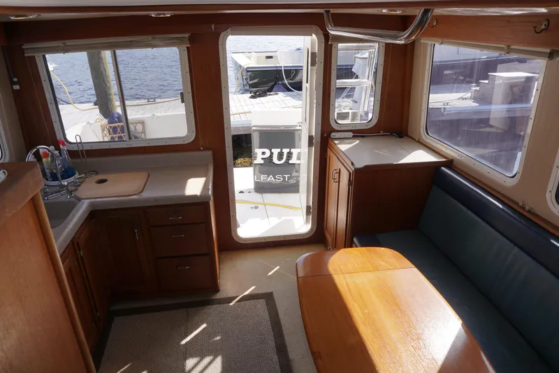 Slide: The Image of Interior of 2004 American Tug 34, featuring kitchen and seating area with waterfront view. - 42