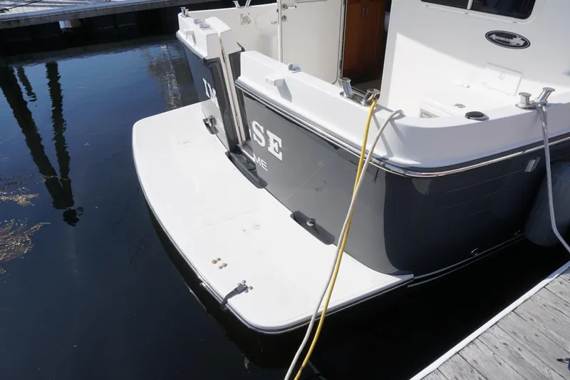 Slide: The Image of 2004 American Tug 34 docked, showing stern and swim platform with mooring lines. - 49