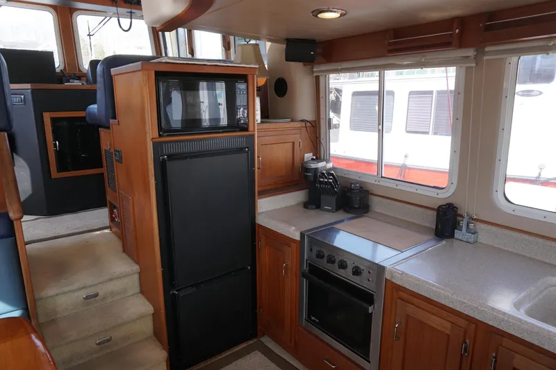 Slide: The Image of Interior of a 2004 American Tug 34, featuring a compact kitchen with appliances. - 5