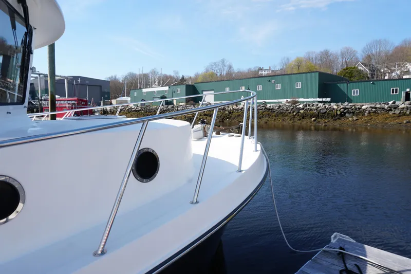 Slide: The Image of 2004 American Tug 34 docked by a calm waterfront with green buildings in the background. - 51