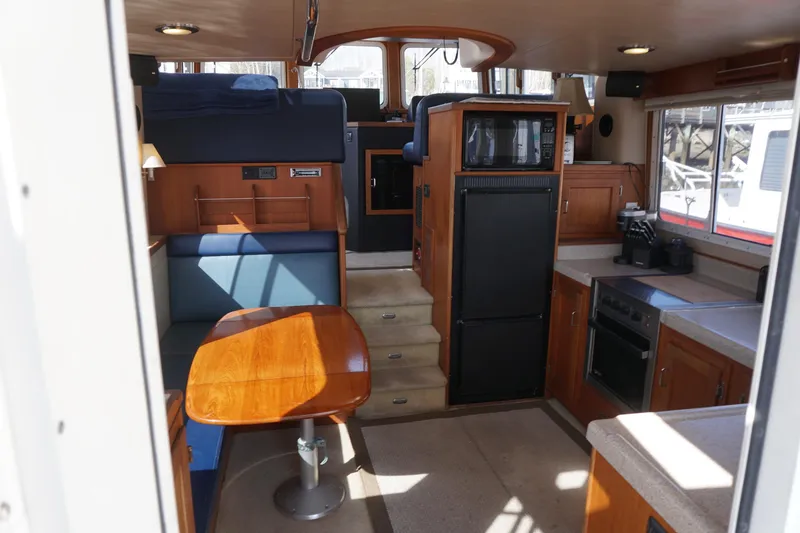 Slide: The Image of Interior of a 2004 American Tug 34, featuring a cozy dining area and modern kitchen amenities. - 7