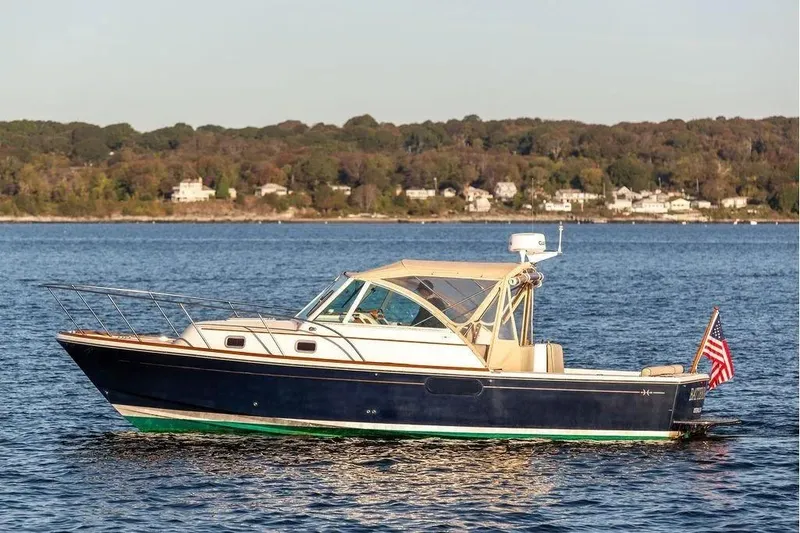 The Image of 2007 Hunt Yachts Surfhunter 29 cruising on a serene lake with forested shoreline. - 1