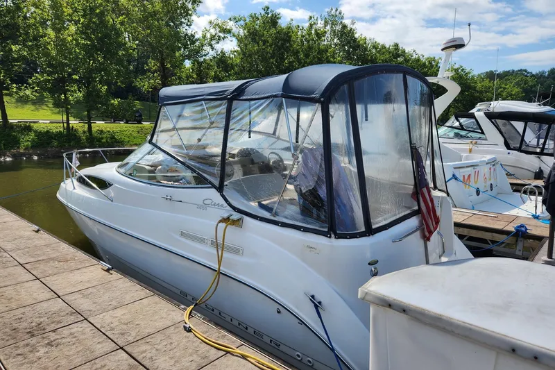 Slide: The Image of 2002 Bayliner 2655 Ciera Sunbridge docked, featuring a covered cockpit and scenic background. - 3