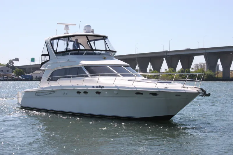 The Image of 2001 Sea Ray 480 Sedan Bridge yacht cruising on a sunny day near a bridge. - 0