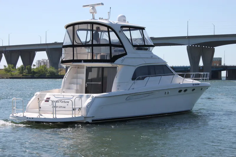 Slide: The Image of 2001 Sea Ray 480 Sedan Bridge yacht cruising under a bridge on a sunny day. - 13