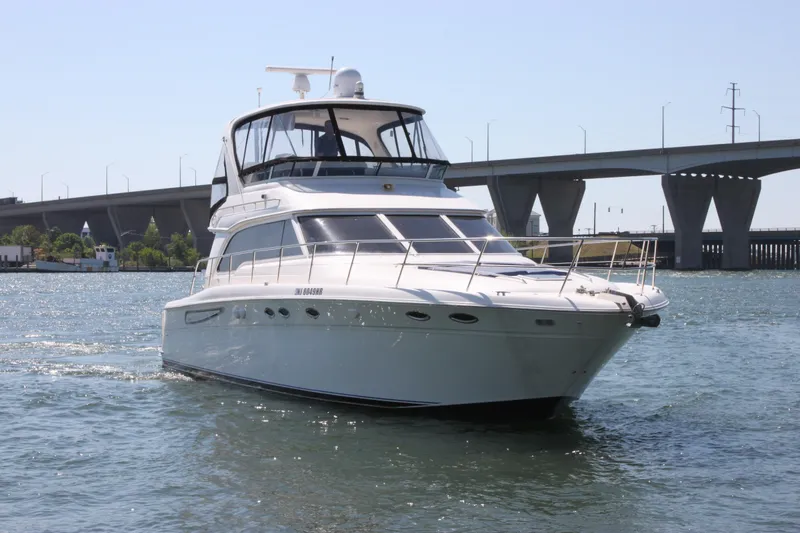 Slide: The Image of 2001 Sea Ray 480 Sedan Bridge yacht cruising near a bridge on a sunny day. - 2