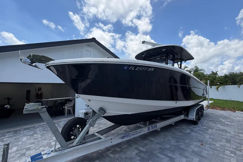 Slide: The Image of 2017 Robalo R302 Center Console boat on trailer, parked near a garage. - 3