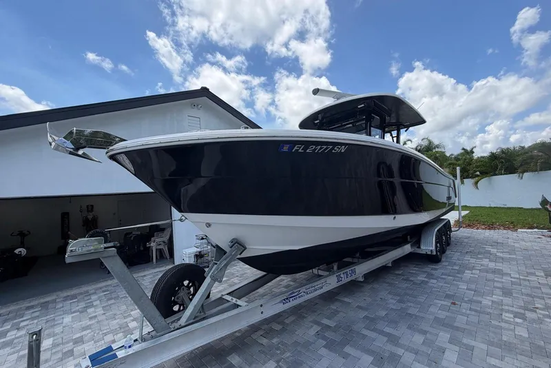 Slide: The Image of 2017 Robalo R302 Center Console boat on trailer, parked in driveway under blue sky. - 4