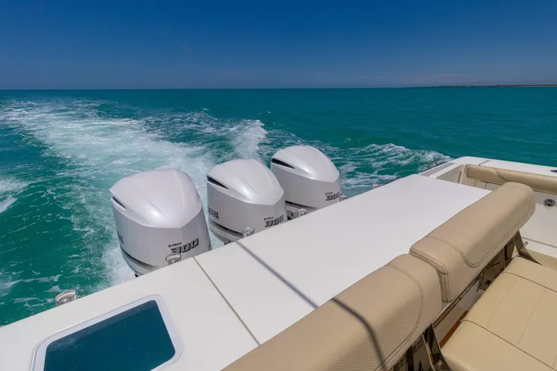 Slide: The Image of 2019 Pursuit OS 385 Offshore boat with triple Yamaha engines cruising on turquoise water. - 11