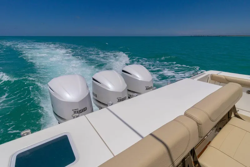 Slide: The Image of 2019 Pursuit OS 385 Offshore boat with triple Yamaha engines cruising on turquoise water. - 12