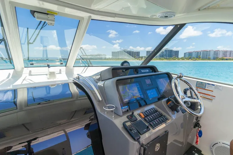 Slide: The Image of 2019 Pursuit OS 385 Offshore helm with navigation screens, steering wheel, and ocean view. - 16