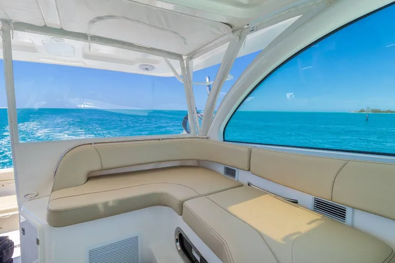 Slide: The Image of 2019 Pursuit OS 385 Offshore boat interior with ocean view and beige seating. - 18