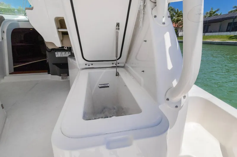Slide: The Image of 2019 Pursuit OS 385 Offshore boat with open storage compartment by the water. - 24