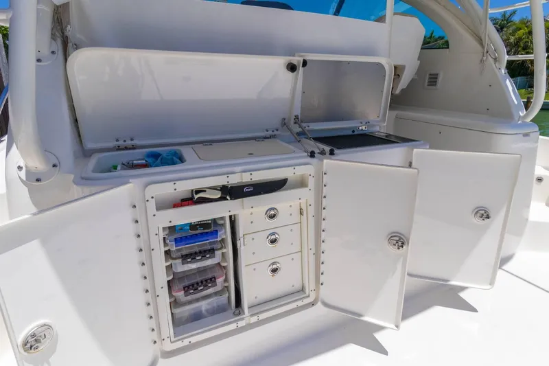 Slide: The Image of 2019 Pursuit OS 385 Offshore boat storage compartments with open doors and organized equipment. - 26