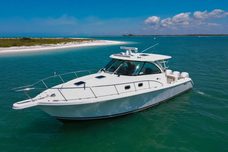 Slide: The Image of 2019 Pursuit OS 385 Offshore boat cruising in clear turquoise waters near a sandy beach. - 3
