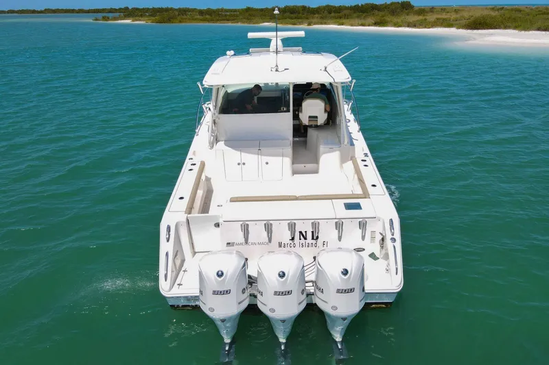 Slide: The Image of 2019 Pursuit OS 385 Offshore boat cruising in clear blue waters near a sandy shore. - 41
