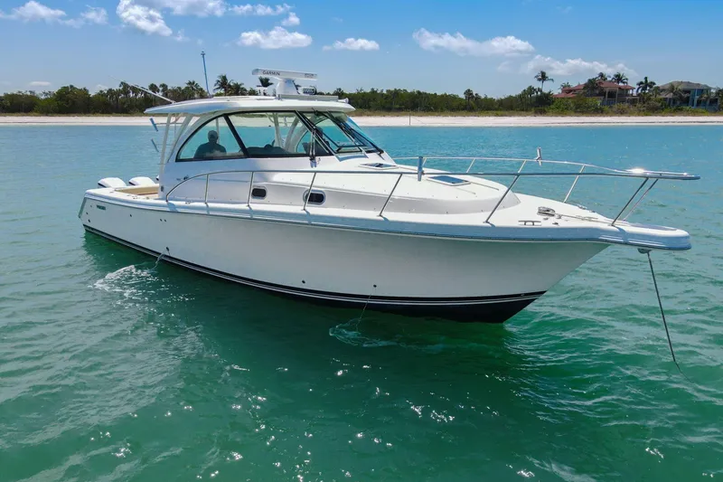 Slide: The Image of 2019 Pursuit OS 385 Offshore boat on calm water near a sandy beach. - 44