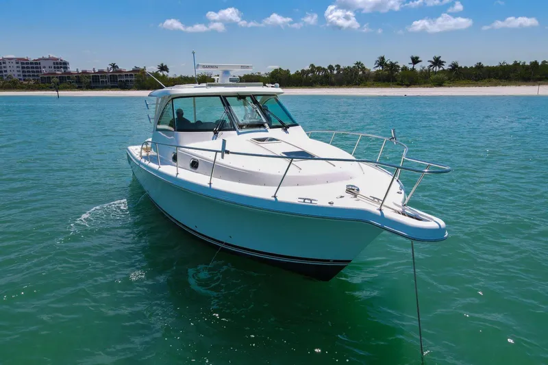 Slide: The Image of 2019 Pursuit OS 385 Offshore boat on clear blue water near a sandy beach. - 45