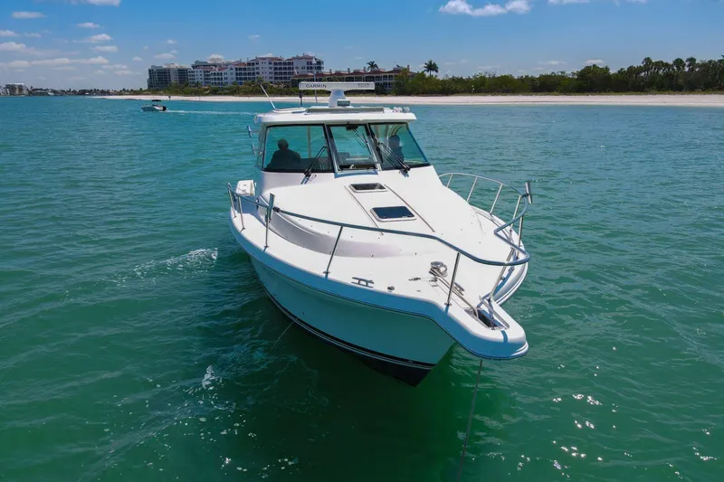 Slide: The Image of 2019 Pursuit OS 385 Offshore boat cruising on clear blue water near a sandy shoreline. - 46