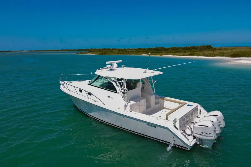 Slide: The Image of 2019 Pursuit OS 385 Offshore boat cruising in clear blue waters near a sandy shoreline. - 49