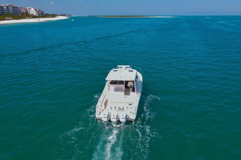 Slide: The Image of 2019 Pursuit OS 385 Offshore cruising in clear blue waters near a sandy shoreline. - 52