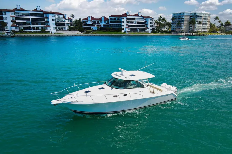 Slide: The Image of 2019 Pursuit OS 385 Offshore cruising in turquoise waters near waterfront buildings. - 53