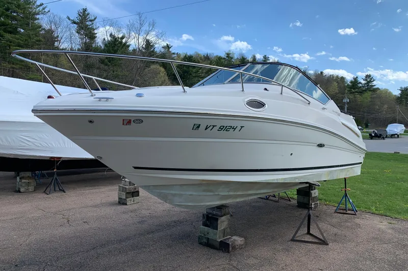 The Image of 2012 Sea Ray 240 Sundancer boat on blocks, parked outdoors under a clear sky. - 0