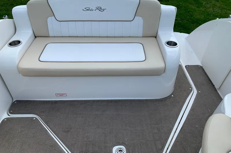 Slide: The Image of 2012 Sea Ray 240 Sundancer boat seating area with beige cushions and cup holders. - 12