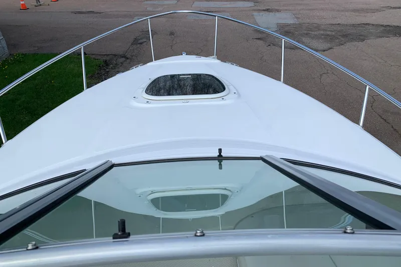 Slide: The Image of 2012 Sea Ray 240 Sundancer boat deck with hatch and railing, docked on pavement. - 15