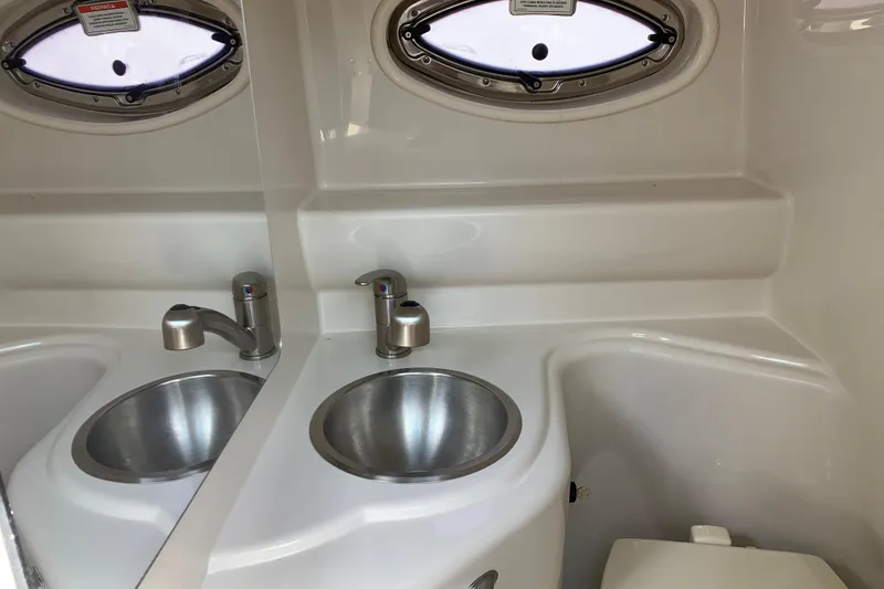 Slide: The Image of Interior of 2012 Sea Ray 240 Sundancer boat bathroom with sink and porthole window. - 24