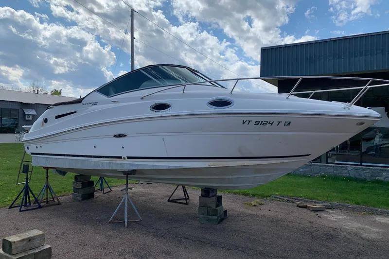 Slide: The Image of 2012 Sea Ray 240 Sundancer boat on stands, outdoors under a cloudy sky. - 3